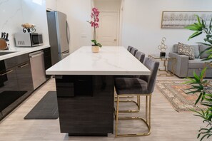 A modern kitchen with a marble countertop, a built-in microwave, and a refrigerator.