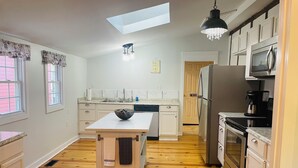 A modern kitchen with a central island, a built-in oven, a microwave, and a refrigerator.