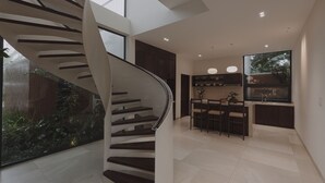A modern interior with a spiral staircase, a kitchen area, and a dining space. - Nhan Stay (Hue)