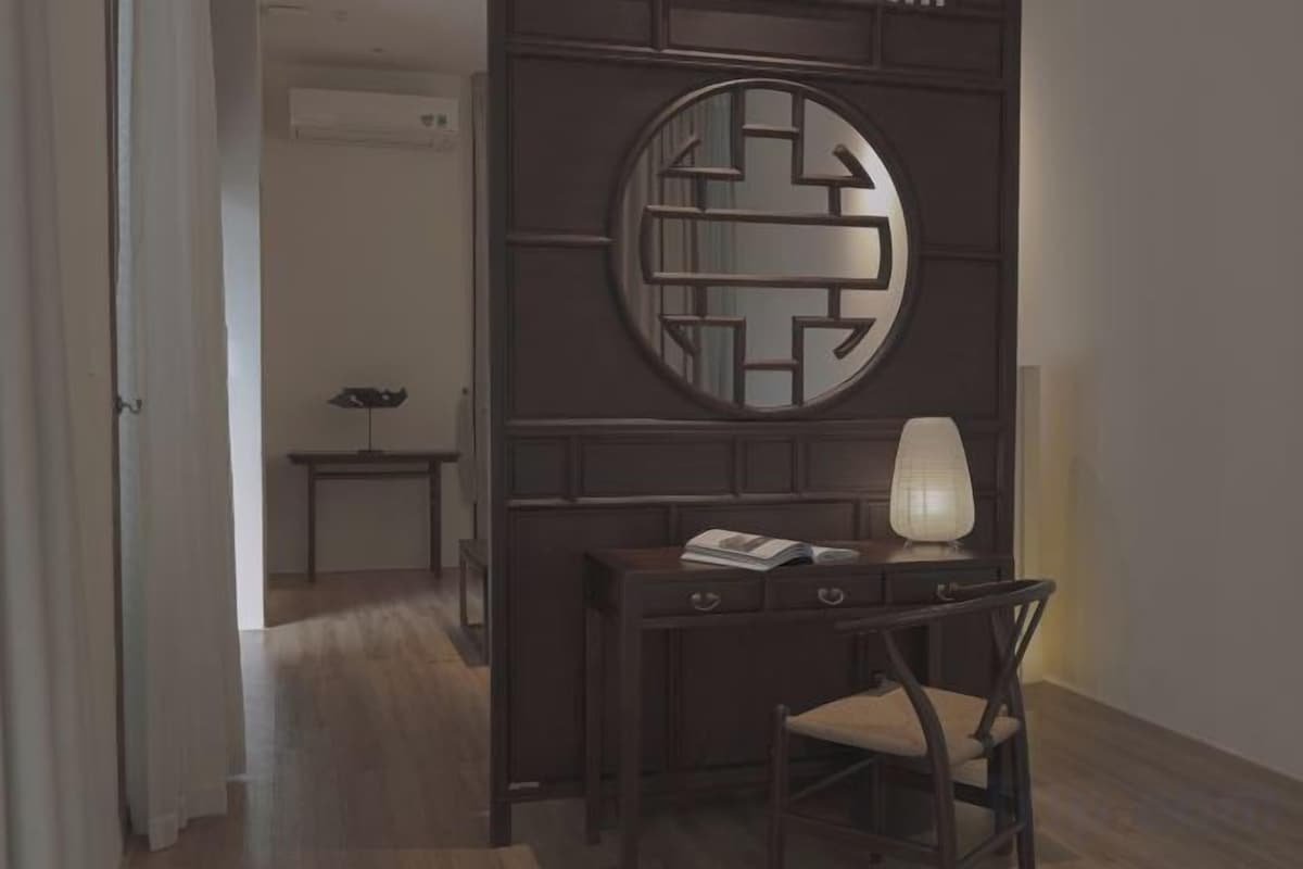 A room with a desk, chair, and a lamp. There is a door leading to another room.