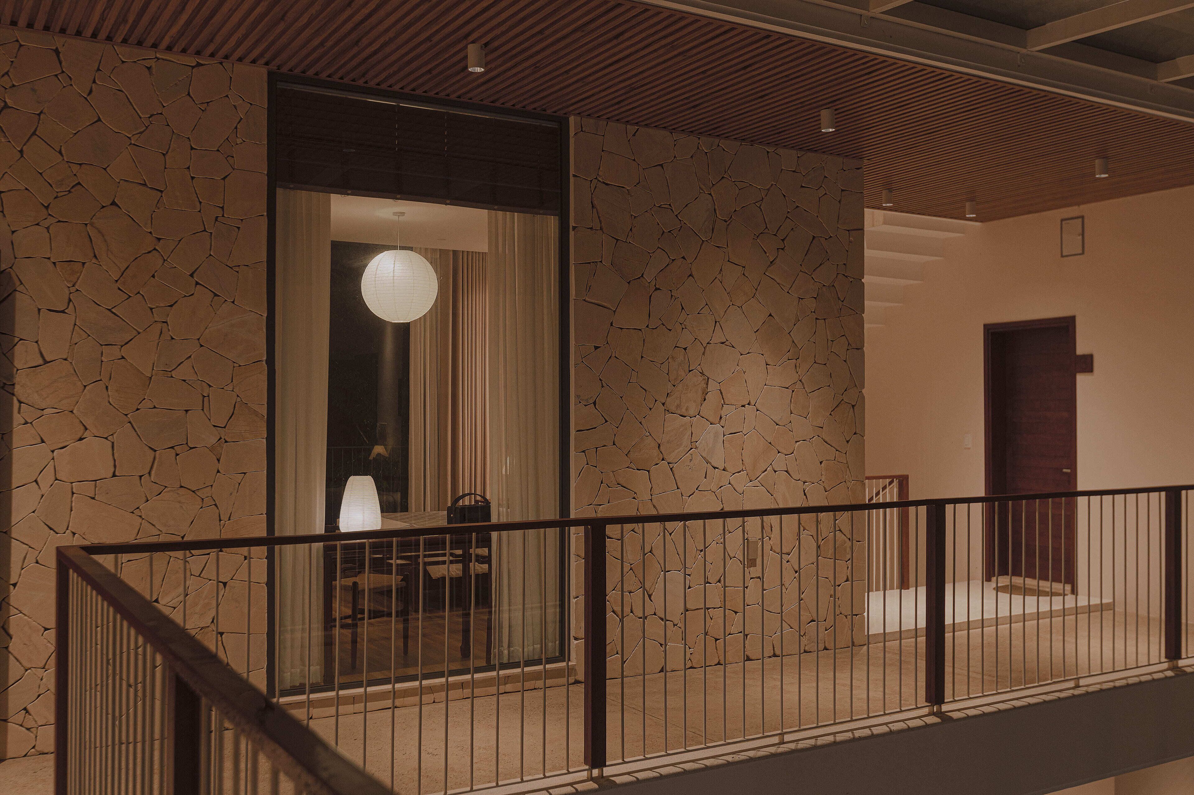Een modern interieur met een stenen muur, een houten plafond en een trap die naar een deur leidt.