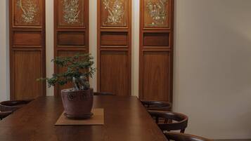 A wooden conference table with a potted bonsai tree in the center, surrounded by chairs.