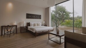 A modern bedroom with a large bed, a desk, a chair, and a view of greenery through a large window. - Nhan Stay (Hue)