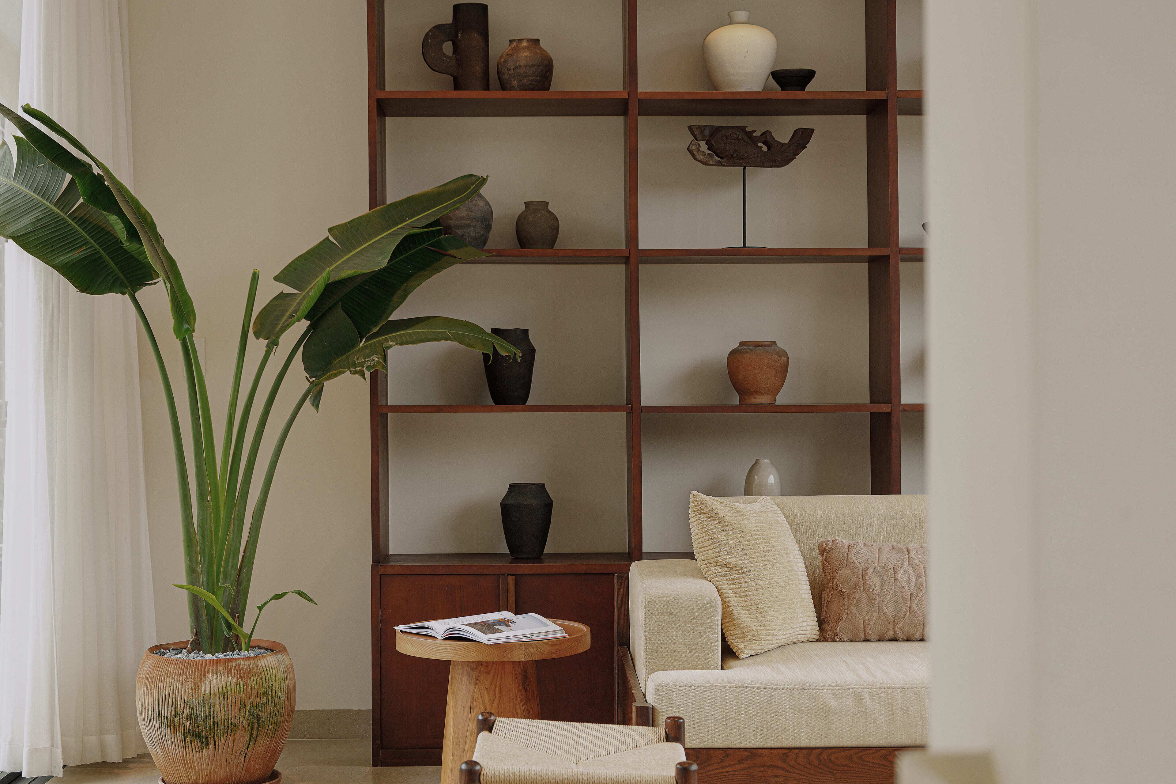 A living room with a sofa, a coffee table, and a bookshelf filled with decorative items.