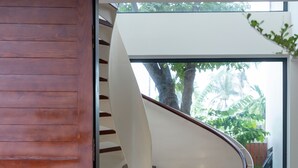 A spiral staircase with a wooden exterior and a white interior, leading to an outdoor area with greenery. - Nhan Stay (Hue)