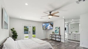A modern bedroom with a bed, a ceiling fan, a TV, and a view of the outdoors. - Petey's Paradise in the Heart of Scottsdale (Scottsdale)