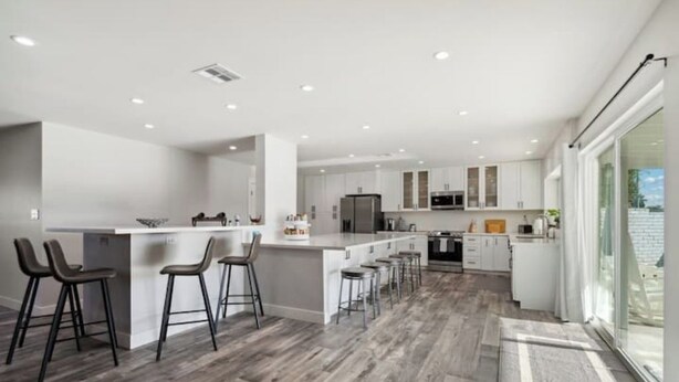 A modern kitchen with a central island, bar stools, and a large window. - Petey's Paradise in the Heart of Scottsdale (Scottsdale)