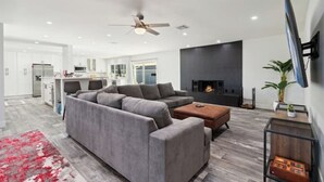 A modern living room with a gray sectional sofa, a coffee table, and a fireplace. - Petey's Paradise in the Heart of Scottsdale (Scottsdale)