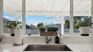 A modern kitchen with a large window, a sink, and potted plants. - Petey's Paradise in the Heart of Scottsdale (Scottsdale)