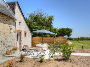 A rustic stone building with a wooden fence, outdoor seating, and a garden area.