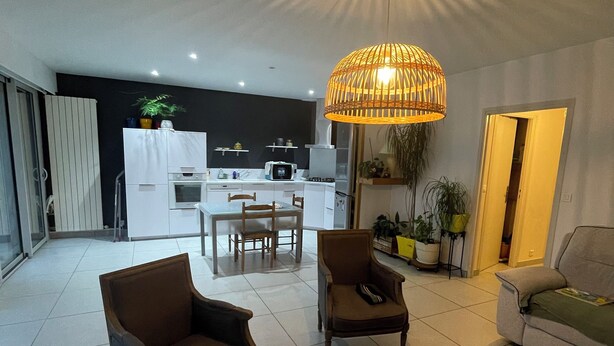 A modern living room with a dining area, a kitchen in the background, and a large window. - Quiet downtown apartment (Rodez)
