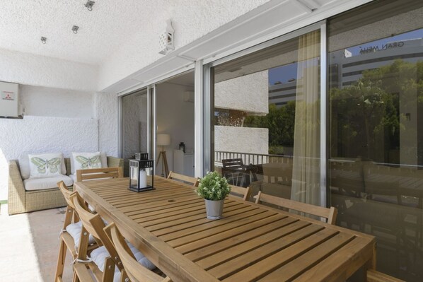 A wooden dining table with chairs, a potted plant, and a glass door leading to an outdoor area.