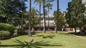 A courtyard with palm trees, a pathway, and a building with multiple floors and balconies. - Isabel Apartment - Golden Mile (Marbella)