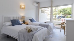 A hotel room with two beds, a desk, and a large window offering a view of the outside. - Isabel Apartment - Golden Mile (Marbella)
