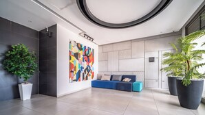 A modern interior with a blue sofa, a large abstract painting, and potted plants. - Beach Haven 3BR Apt by Sea N' Rent (Nahariya)