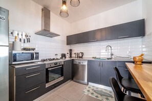 Uma cozinha moderna com eletrodomésticos de aço inoxidável, armários pretos e uma mesa de jantar de madeira.