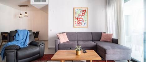 A modern living room with a grey sectional sofa, a wooden coffee table, and a red and white patterned rug.