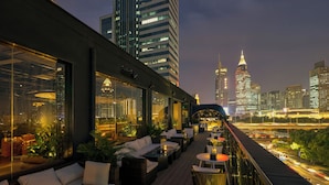A rooftop bar with outdoor seating, city views, and modern architecture.