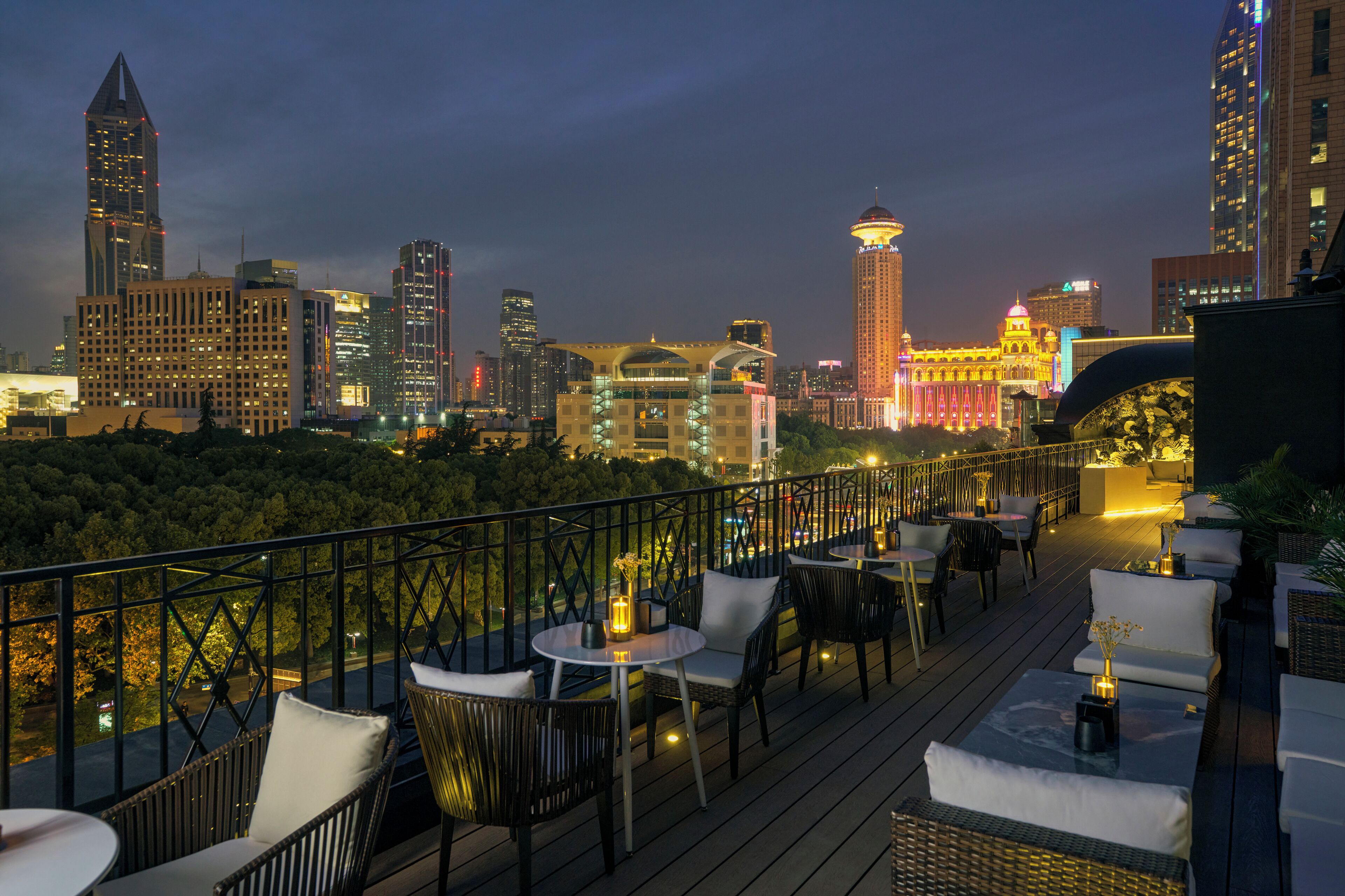 A rooftop terrace with outdoor seating, a city skyline in the background, and a view of the water.