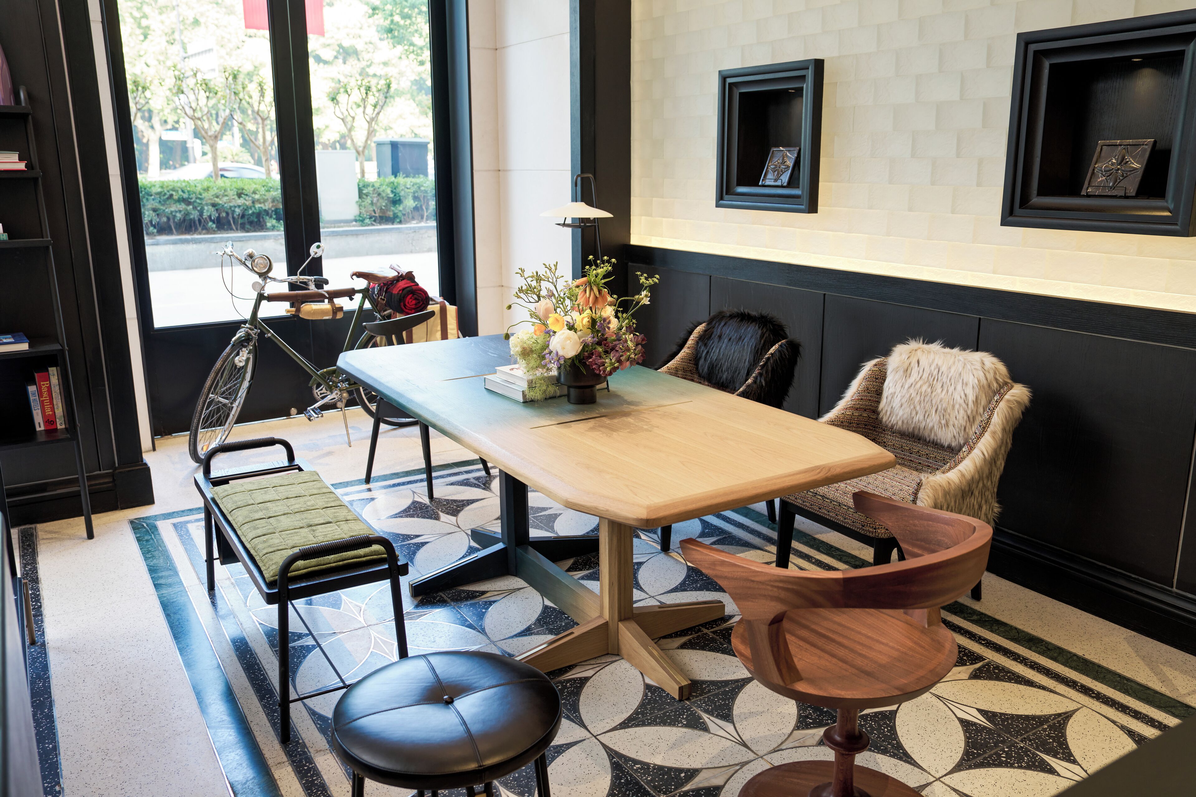 A modern interior with a wooden table, chairs, a bench, and a patterned floor.