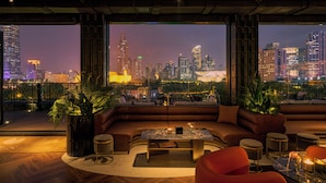 A modern living room with a large window overlooking a city skyline at night. - OPARTMENT The Far Eastern Hotel - People's Square (Shanghai)