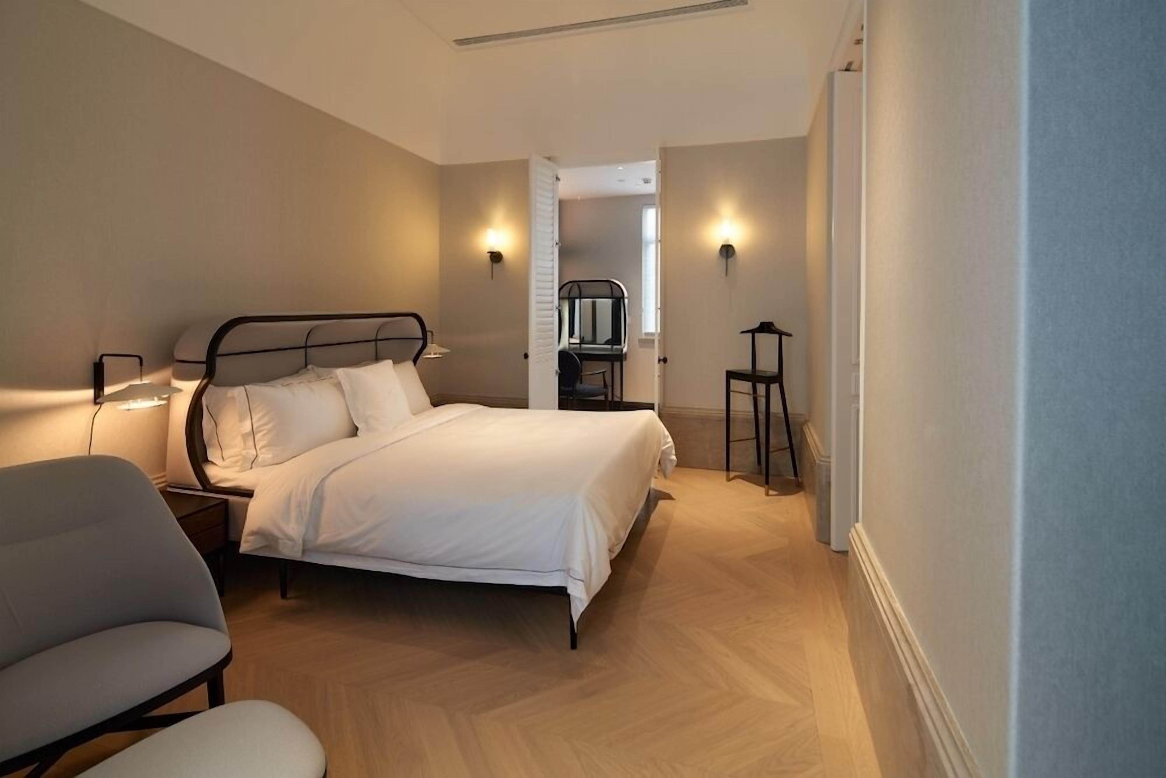 A bedroom with a bed, bedside tables, a chair, and a desk.
