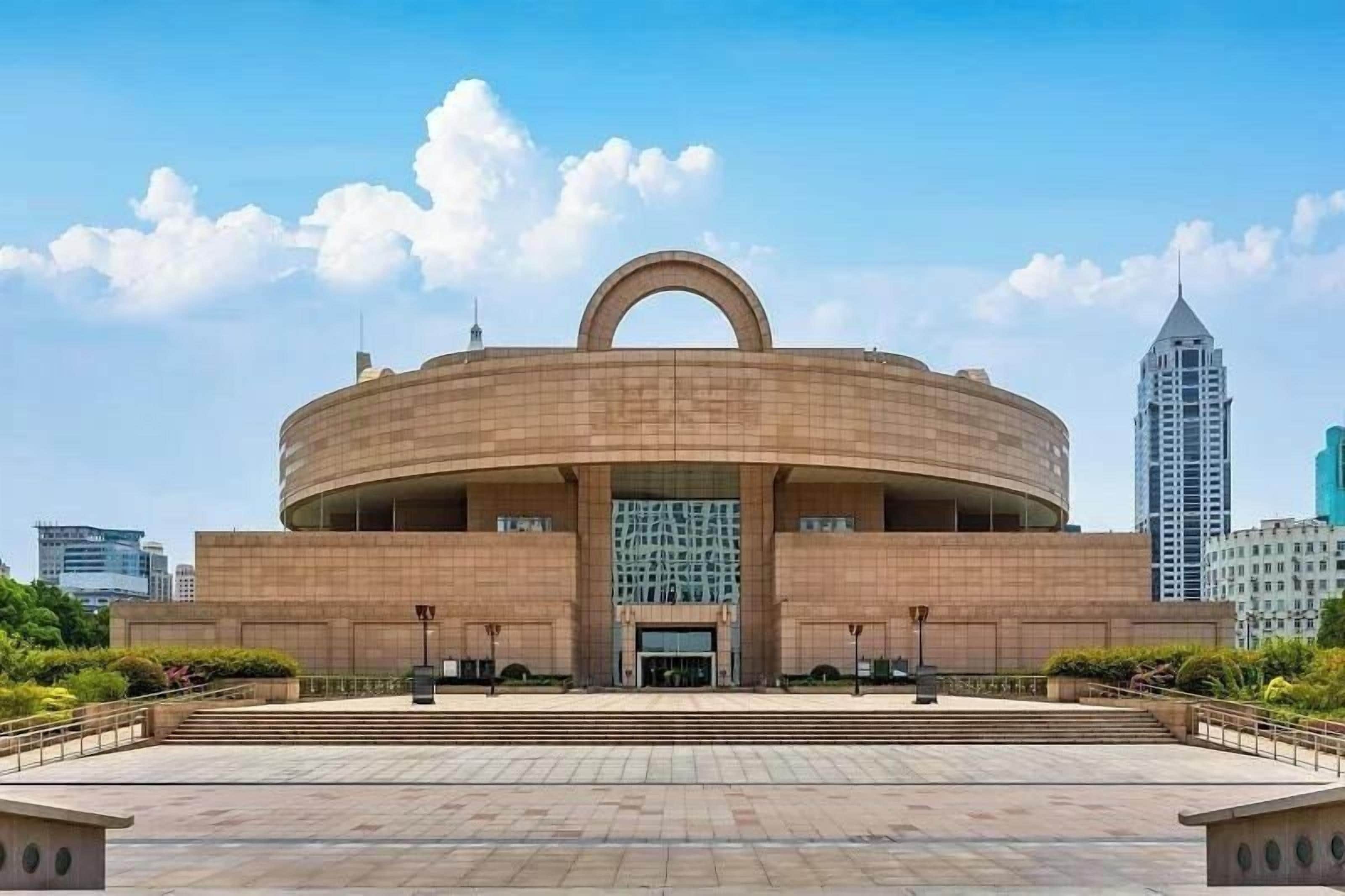 A large, circular building with a central archway, surrounded by a paved plaza.