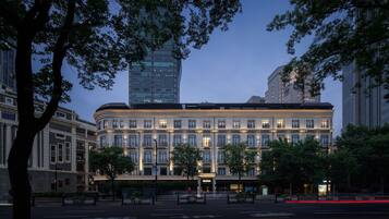 Een meerhoog hotel met een klassiek architectuurontwerp, met een centrale binnenplaats en een modern gebouw op de achtergrond.