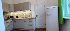 A compact kitchen with a microwave, sink, and a white refrigerator. - Modern apartment with a fireplace, an electric vehicle charging station, and free parking (Schwerin)