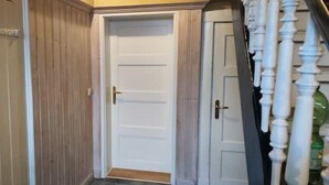 Un pasillo con una puerta de madera y una puerta blanca con un panel de vidrio.