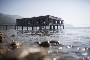 Um edifício moderno sobre pilares, acima da água, com vista desobstruída da paisagem ao redor.