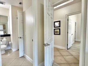 Un couloir avec des toilettes, un lavabo et un miroir dans une salle de bain.