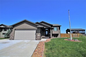 A two-story house with a garage, a stone accent wall, and a well-maintained lawn.