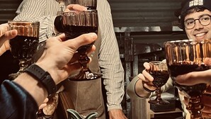 Un groupe de personnes trinquant avec des verres de vin autour d’une table ornée d’une sculpture de poisson décorative et d’une assiette de nourriture.