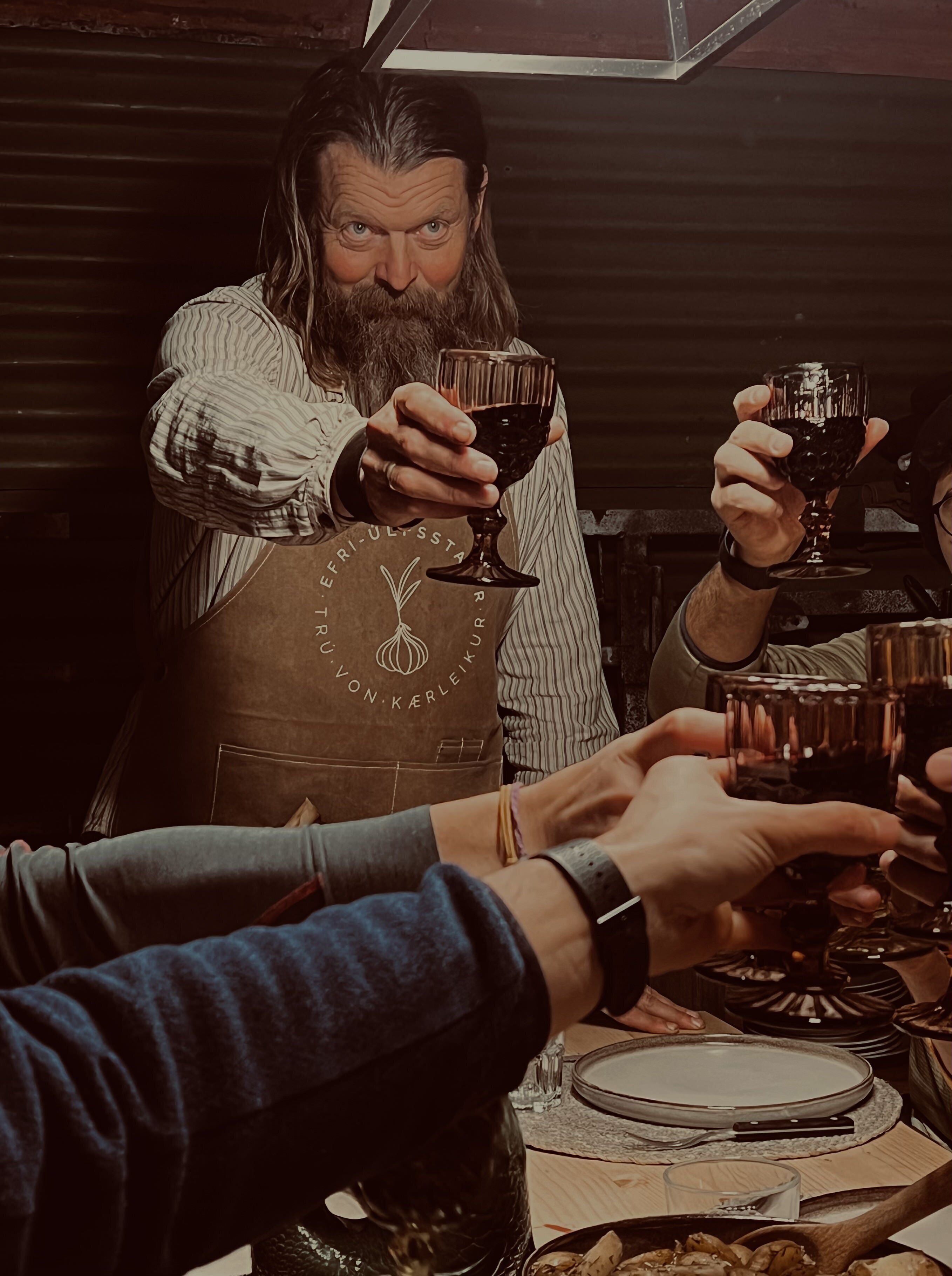A person in a striped shirt and apron holding a wine glass.