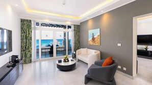 A modern living room with a sofa, armchair, and coffee table. There is a large window with a view of the sea. - Naama Bay Suites & Spa (Sharm El Sheikh)