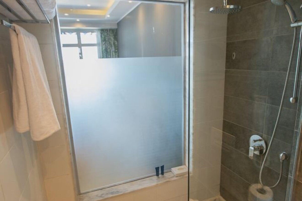 A modern bathroom with a glass shower enclosure, a towel rack, and a toilet paper holder.