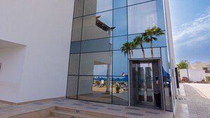 A modern building with a glass facade, a set of outdoor stairs, and a clear sky. - Naama Bay Suites & Spa (Sharm El Sheikh)