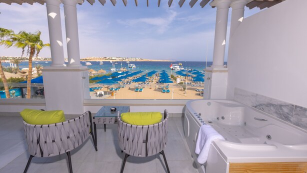 A balcony with a view of the beach, a jacuzzi, and two chairs with cushions. - Naama Bay Suites & Spa (Sharm El Sheikh)