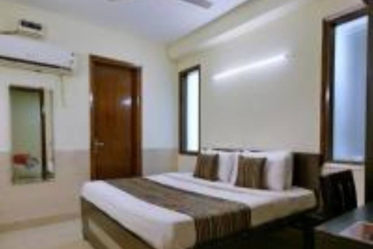 A bedroom with a bed, a desk, and a window.