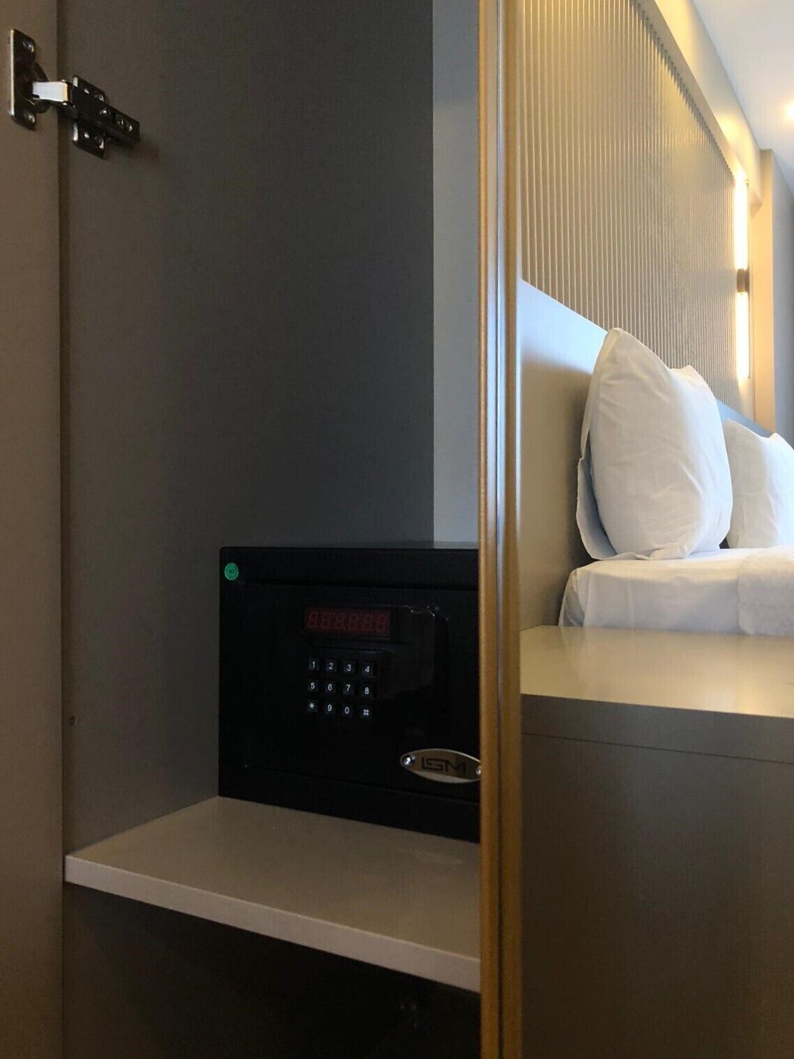 Habitación de hotel con cama, panel de control y lámpara fijada a la pared.
