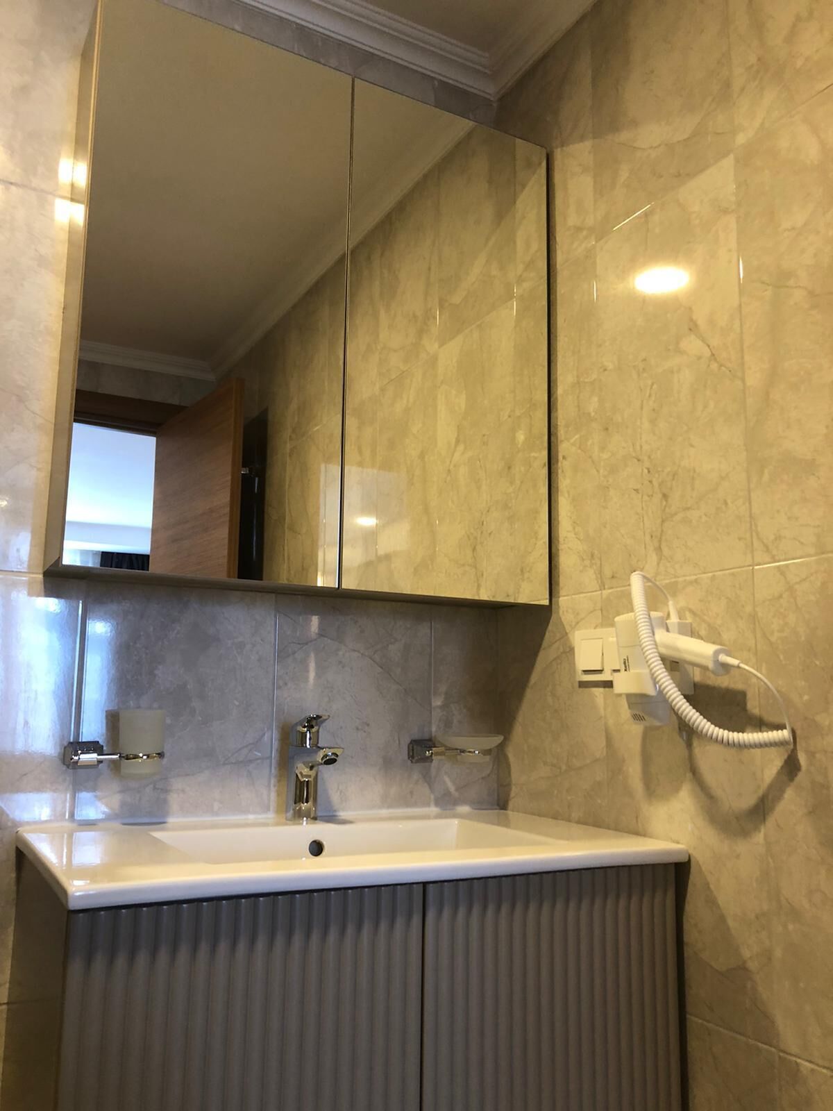 Une salle de bain avec un grand miroir, un lavabo et un sèche-serviettes.