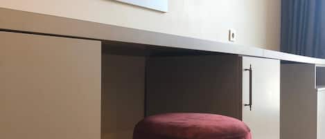 En moderne opholdsstue med et fladskærms-tv på væggen, en rund, rød skammel og et minimalistisk design.