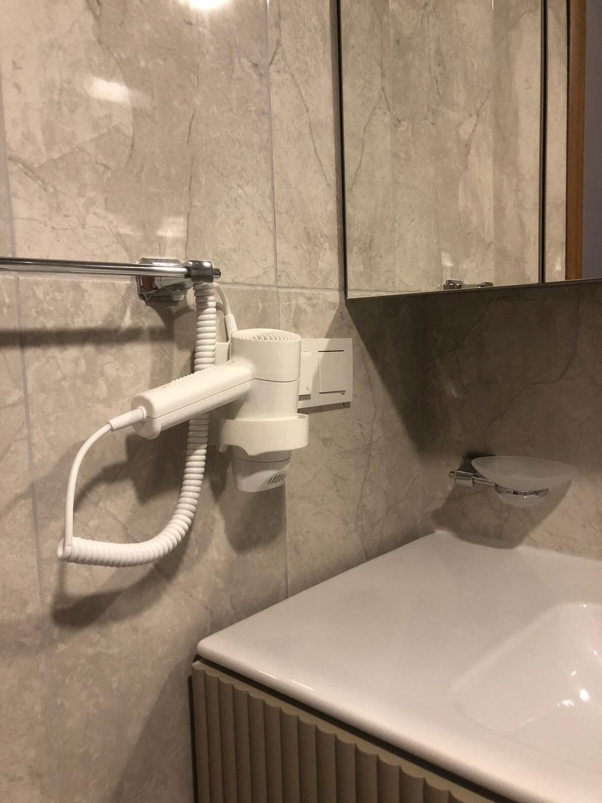 A bathroom with a white sink, a towel rack, and a shower head.