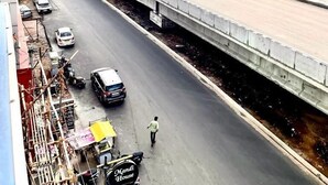 A multi-level highway with vehicles, a pedestrian, and buildings in the background. - HOTEL SITA GRAND (Hyderabad)