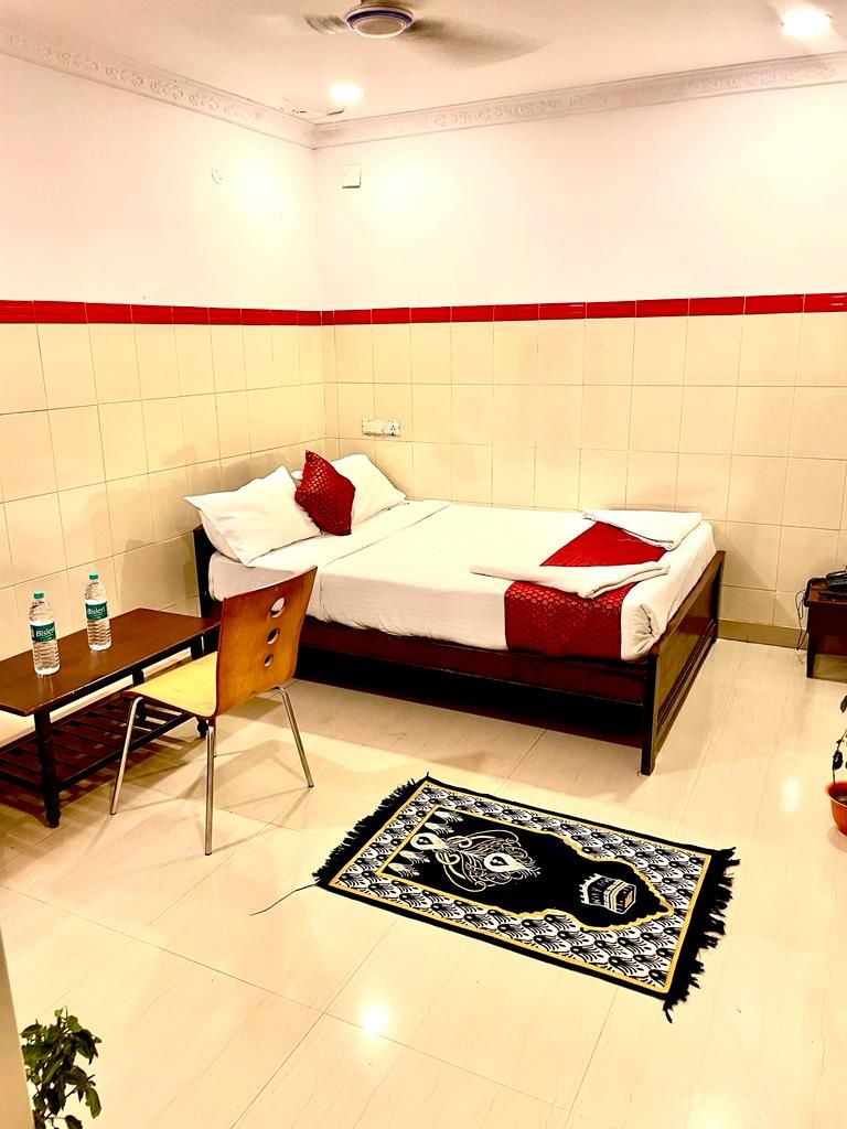 Una habitación de hotel con cama, una silla, una mesa y un tapete decorativo.