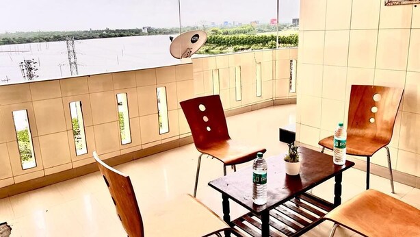 A balcony with a view of a river, a satellite dish, and a table with chairs and a bottle of water. - HOTEL SITA GRAND (Hyderabad)