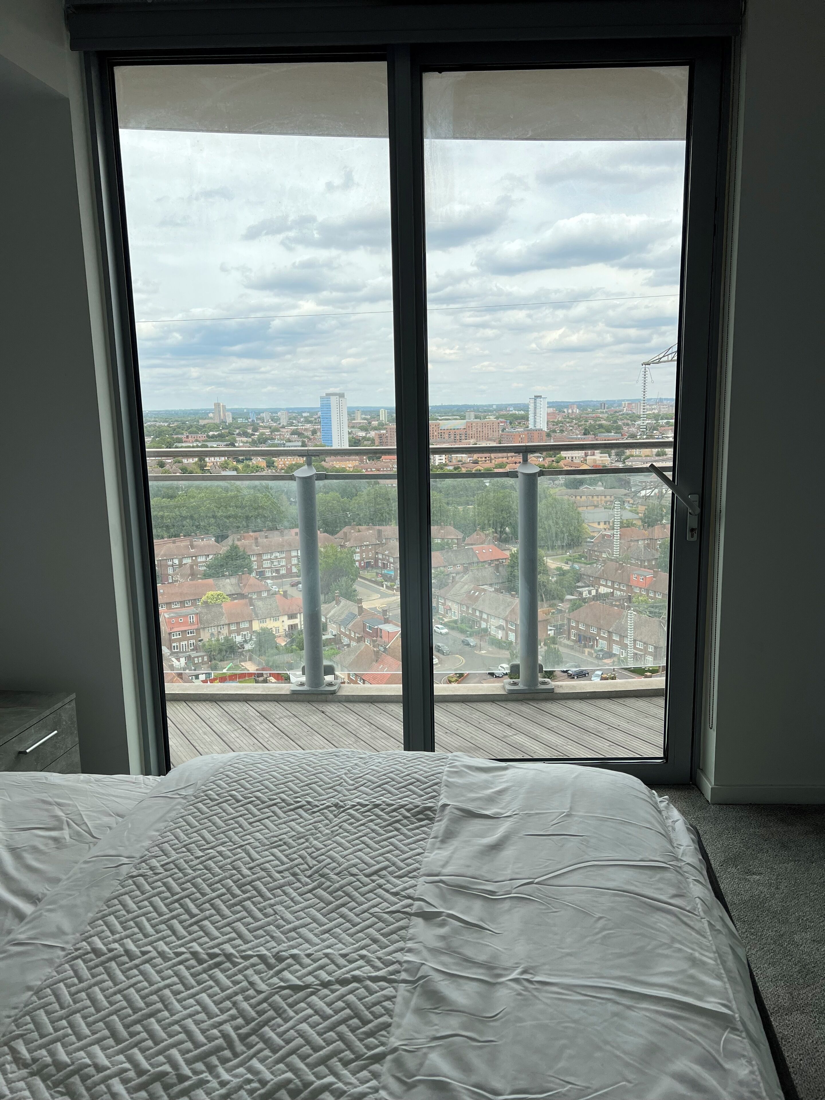 A bedroom with a large window overlooking a cityscape.