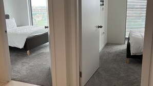 Ein Hotelzimmer mit Bett, einem Fenster mit Jalousien und Blick auf die Stadtlandschaft.