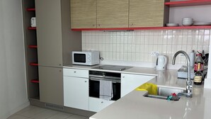 Eine moderne Küche mit weißen Schränken, einer Mikrowelle, einem Wasserkocher und einem Spülbecken.